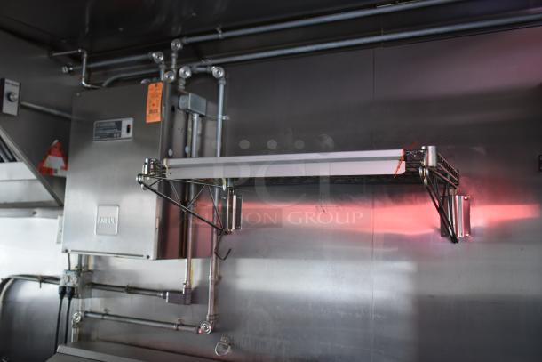 Interior view of ATX 28' cold food trailer featuring a metal utility shelf, stainless steel surfaces, and electrical fixtures.