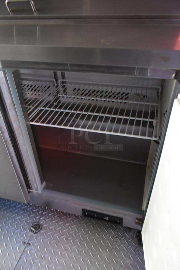 Inside view of ATX 28' unbranded trailer with commercial Arctic Air cooler, featuring wire shelving and diamond plate flooring.