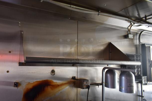 Interior view of a 2020 ATX 28' unbranded food trailer. Features commercial-grade stainless steel surfaces, electrical outlets, and overhead grease hood.