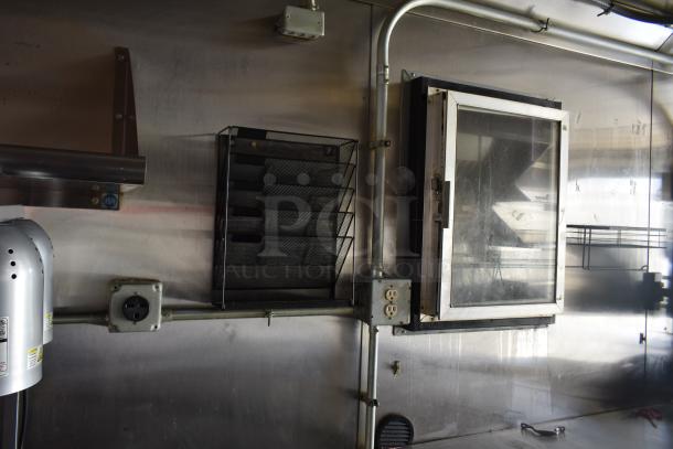 Interior view of unbranded 28' ATX cold food trailer showing utility outlets and equipment racks. Stainless steel walls.