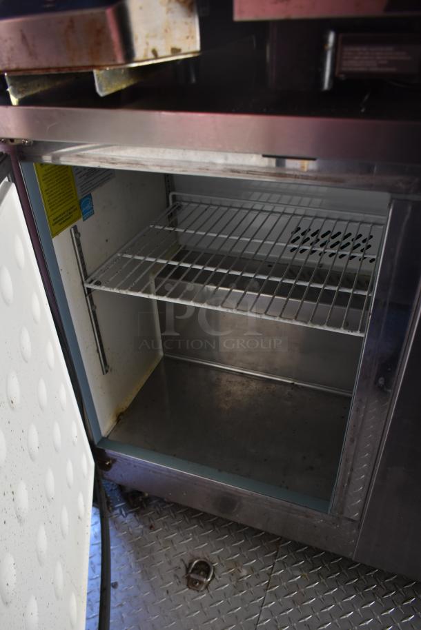 ATX 28' food trailer interior with open Arctic Air cooler, metal racks, and diamond plate flooring, showing slight wear.