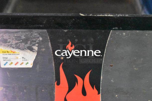 Close-up of a "cayenne" logo and a faded "Use By" label on dark equipment, indicating branding and usage instructions.