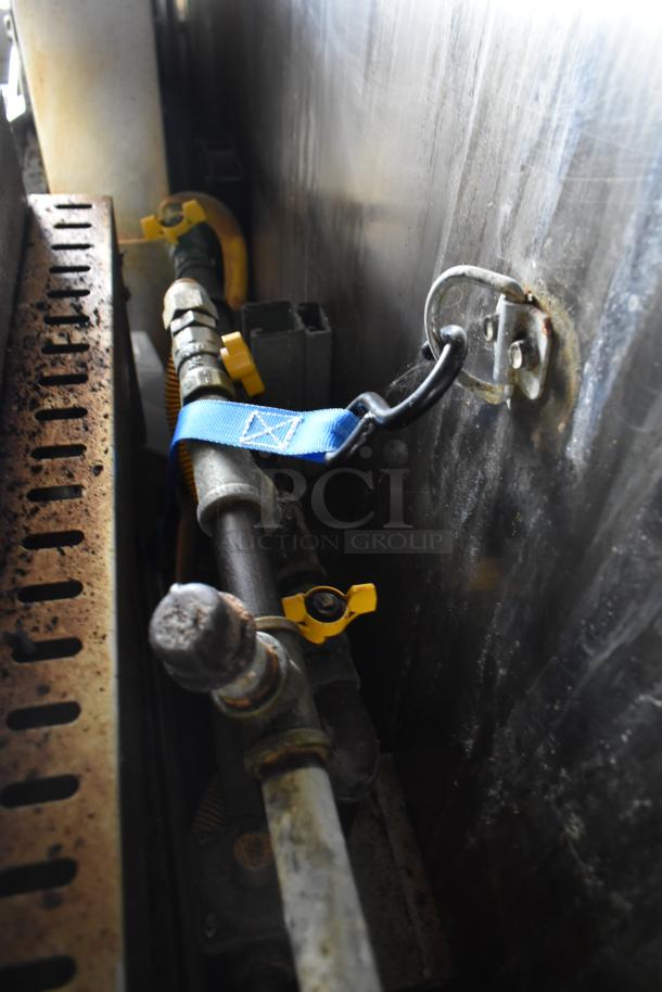 Close-up of a pipe with a blue strap and yellow valves inside the ATX 28' food trailer. Industrial setting.