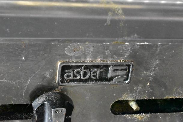Close-up of Asber logo on commercial kitchen equipment, showing slight wear.
