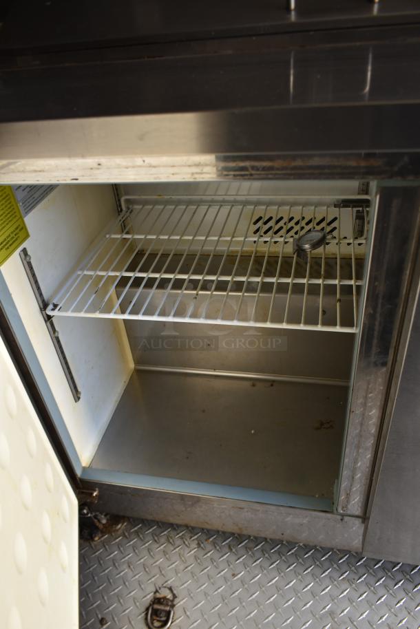 Interior view of fully equipped ATX 28' unbranded cold food and beverage trailer. Arctic Air cooler with wire shelf visible.