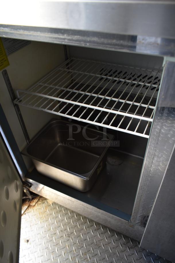 ATX 28' food trailer internal view, showing stainless steel cabinet with wire shelf and food pan on diamond plate flooring.