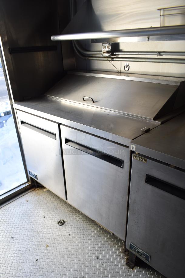 ATX 28' cold food trailer interior, featuring Arctic Air prep table, cooler, freezer, grease hood; ready for operation.