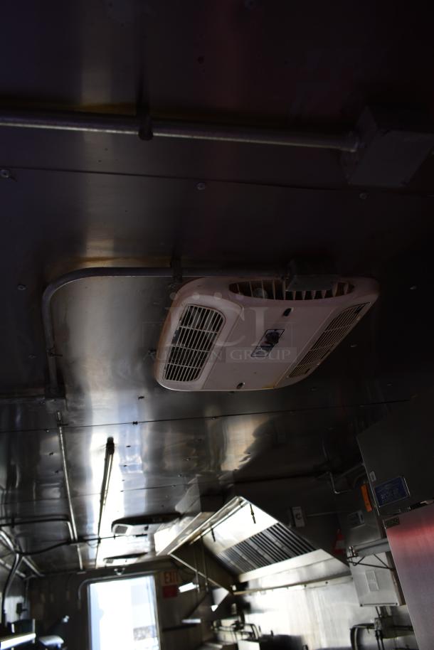 Interior view of an ATX 28' food and beverage trailer, featuring commercial-grade equipment like Arctic Air prep tables and coolers, and a grease hood.