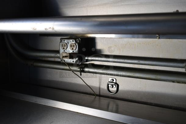 Interior detail of ATX 28' food trailer showing metal pipes, electrical outlet, and hook. Commercial fitment in stainless steel.