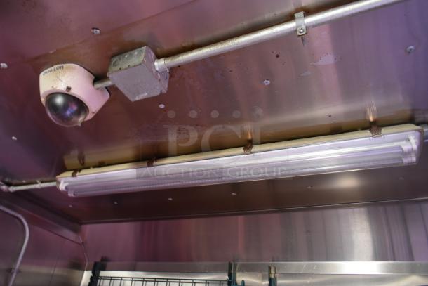 Interior of ATX 28' food trailer, featuring ceiling security camera and fluorescent lighting. Clean metallic surfaces visible.