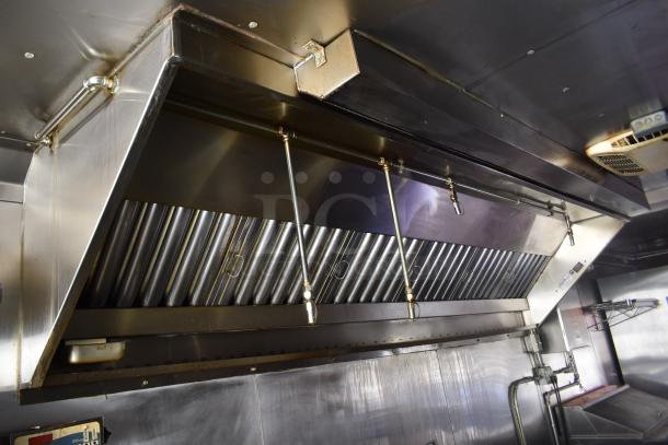 Stainless steel grease hood with suppression system in ATX 28' cold food and beverage trailer, featuring modern fixtures.