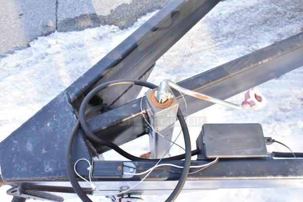Trailer hitch and wiring components of an unbranded cold food and beverage retail trailer, new in 2021, shown in a snowy setting.