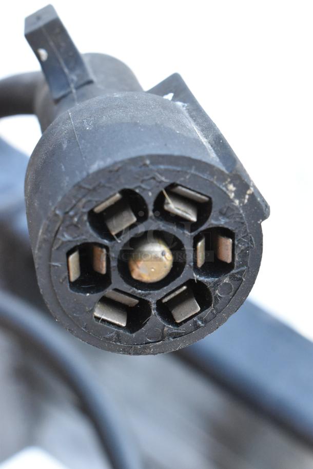 Close-up image of a black multi-pin connector, showing metallic pins and slight surface wear.