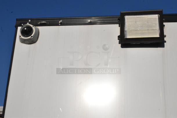 Exterior of unbranded cold food and beverage trailer with security camera and exterior light fixture visible.