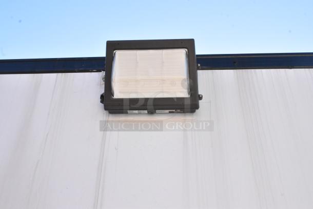 Exterior detail of the unbranded cold food and beverage trailer, focus on mounted outdoor light fixture against a blue sky.