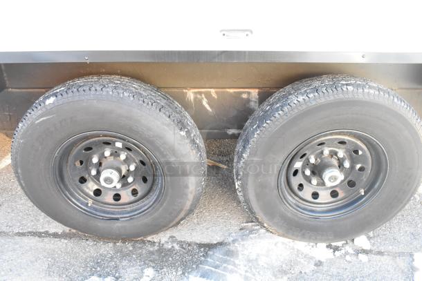 Dual black wheels of a retail trailer, showcasing sturdy tires on pavement.