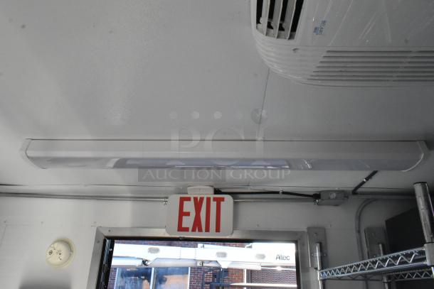 Interior of a fully outfitted cold food and beverage retail trailer. Features include ceiling-mounted AC, exit sign, and shelving. Perfect for diverse concepts.