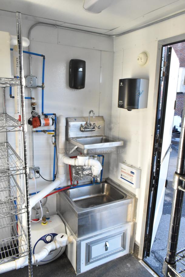 Fully outfitted food and beverage trailer interior with sink, shelving, and commercial equipment. New in 2021, pristine condition.