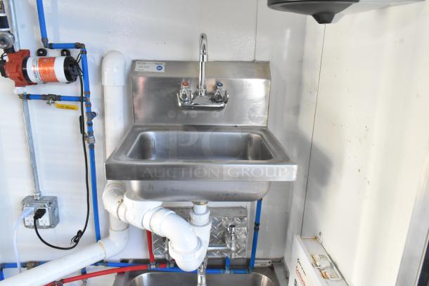 Commercial sink setup in unbranded food trailer, featuring stainless steel basin, faucet, and plumbing. Ideal for cold food service.