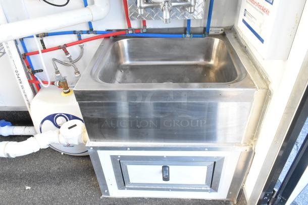 Stainless steel sink with storage, part of a fully equipped unbranded food and beverage retail trailer.