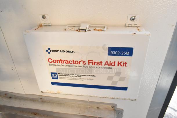 Contractor's First Aid Kit, 25-person capacity, meets OSHA requirements, mounted on white interior surface, slightly rusted.
