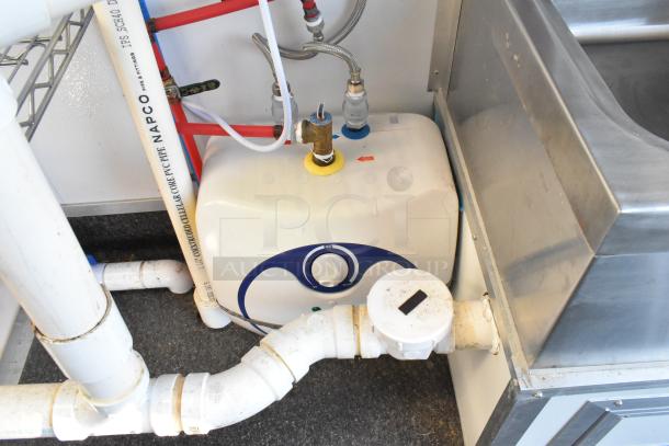 Unbranded cold food trailer interior showing plumbing and water heater, includes IPS SCH40 PVC pipe and stainless sink.
