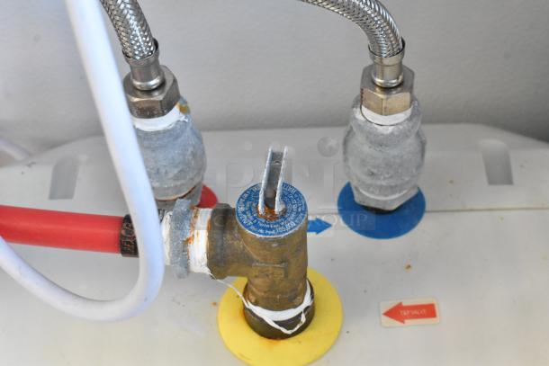 Close-up view of plumbing connections and valve with red, blue, and white pipes, possibly part of the trailer’s equipment system.