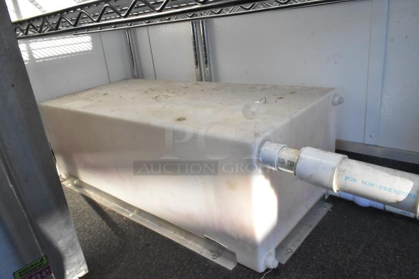 Cold food and beverage retail trailer interior, showing a water tank with attached PVC piping, clean and ready for use.