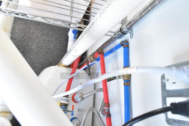 Pipes and wiring inside a fully outfitted cold food and beverage retail trailer, showing plumbing details and connectivity.