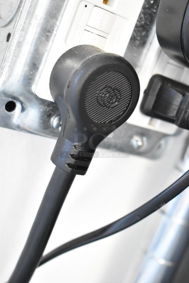 Close-up of a black power cord connected to a metal outlet, part of a 2021 unbranded food trailer equipment setup.