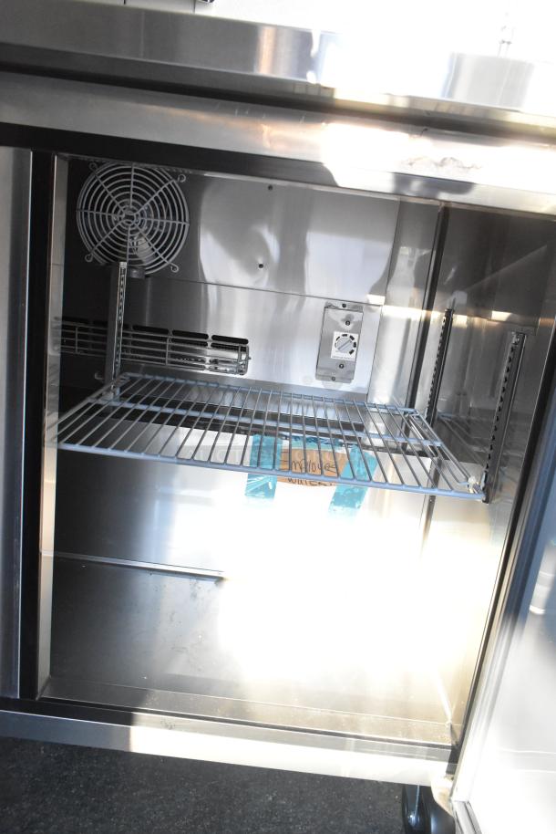 Interior view of a commercial-grade cooler in a fully equipped food and beverage trailer, featuring shelving and ventilation.
