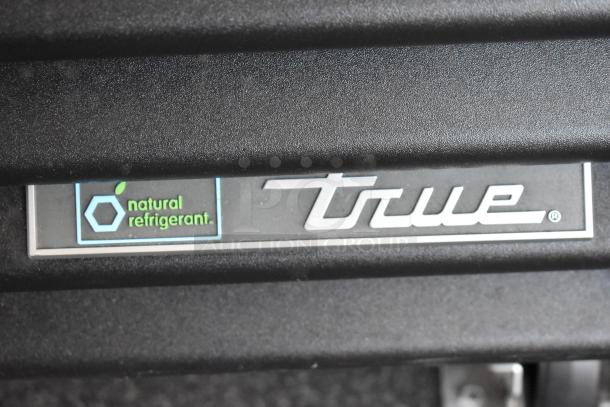 Label inside a food and beverage trailer indicating "natural refrigerant" and "True" branding on equipment.