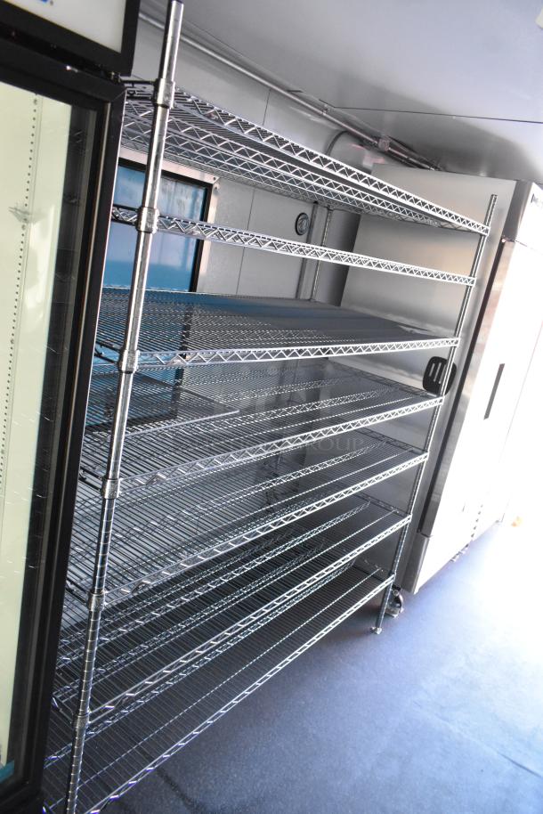 Unbranded cold food trailer interior with stainless steel shelving, commercial True freezer, and cooler merchandisers. Clear title.