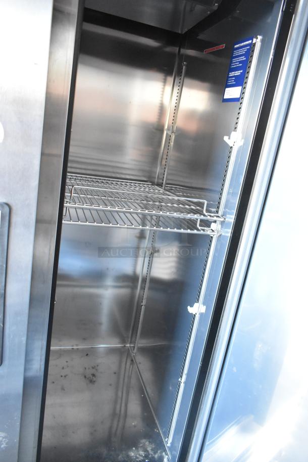 Interior view of a stainless steel commercial cooler with wire shelving, part of a fully outfitted 2021 retail trailer.