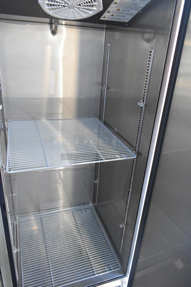 Inside view of an unbranded commercial-grade cooler with wire shelves, fan, and metal interior, part of a 2021 retail trailer.