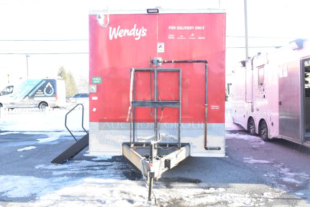 Alt text: Red Titanium Cargo 28' shell food trailer with security system, labeled for delivery, featuring security details and setup for equipment.