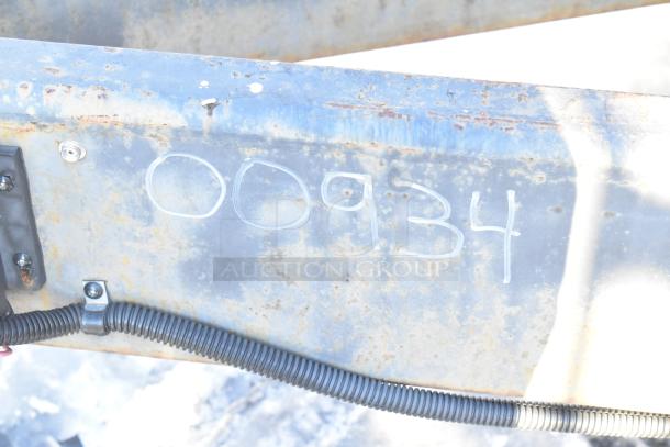 Rusty trailer metal surface with the number "00934" marked in white. Black cable attached below.
