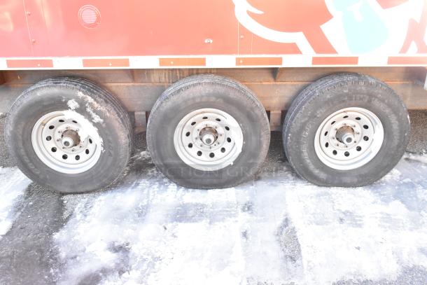 Titanium Cargo 28' food trailer wheels on icy ground, featuring triple axles. Trailer ready for mobile kitchen setup.