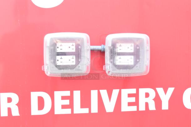 Close-up of dual outdoor electrical outlets on the red Titanium Cargo 28' food trailer, equipped with protective covers.