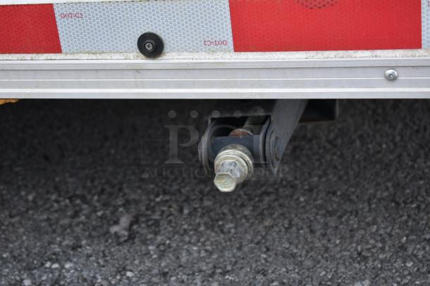 Close-up of a Nationwide 24' shell food trailer hitch bolt, showing the underside frame and reflective DOT-C2 tape.