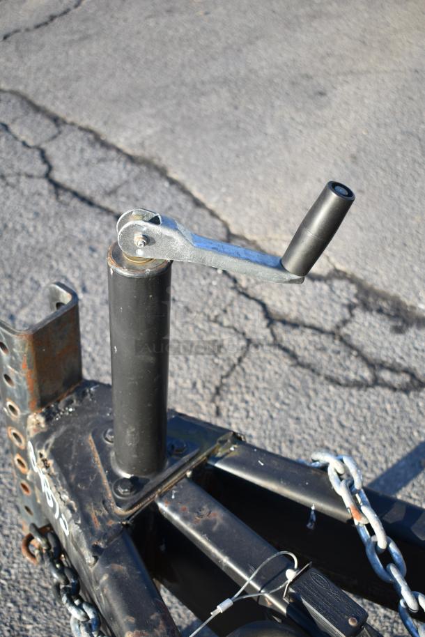 Close-up of a 2021 Nationwide 24' food trailer hitch. Features durable build, metal chains, and sturdy lever handle.