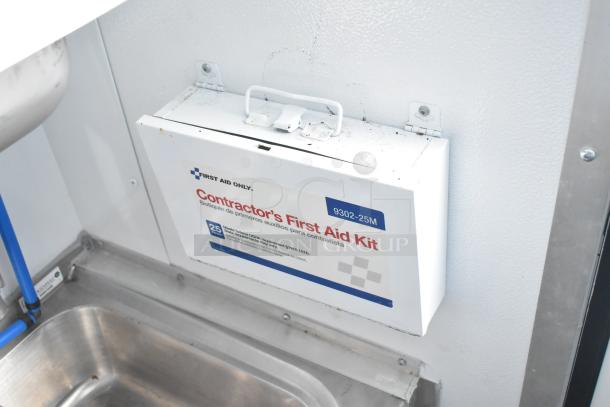 Contractor's First Aid Kit mounted in a food and beverage trailer. Includes 25 pieces for emergencies.