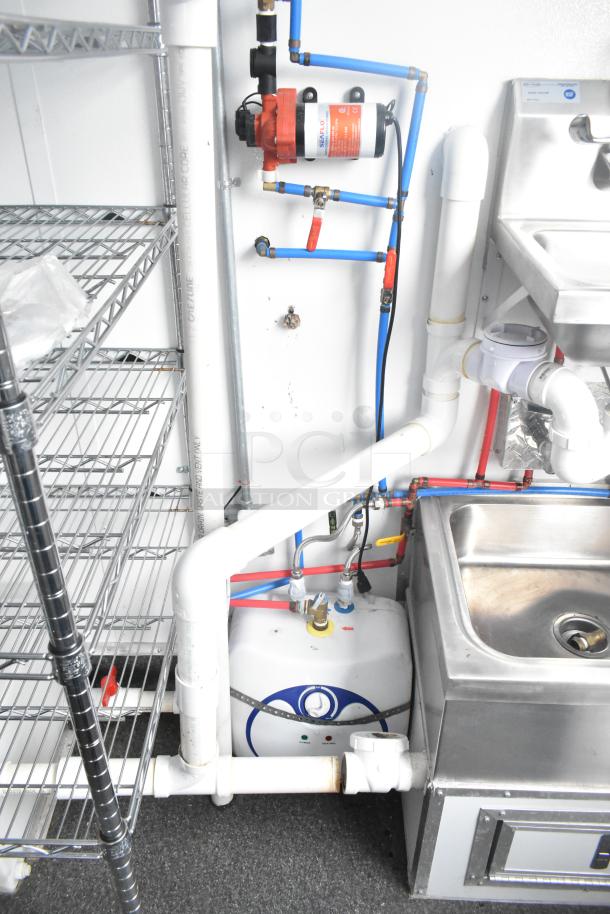 Fully outfitted cold food and beverage trailer interior with stainless steel sink, shelving, and visible plumbing setup.