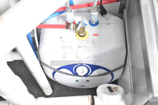 Compact commercial water heater inside a fully equipped retail trailer, with visible pipes and connections.