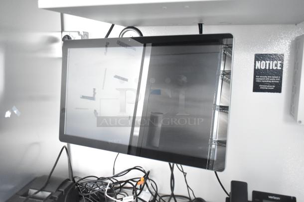 Interior of a retail trailer showcasing a screen monitor, various cables, and a notice about security recording.