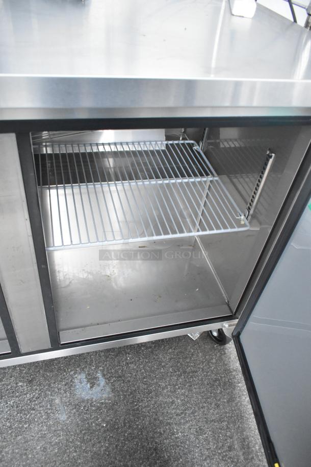 Interior view of a new unbranded cold food and beverage trailer, featuring a Turbo Air cooler with wire shelving.