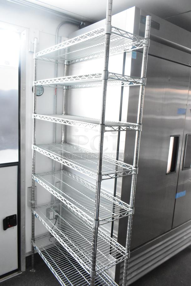 Unbranded cold food and beverage trailer interior featuring metal shelving and stainless steel commercial-grade cooler, 2021 model.