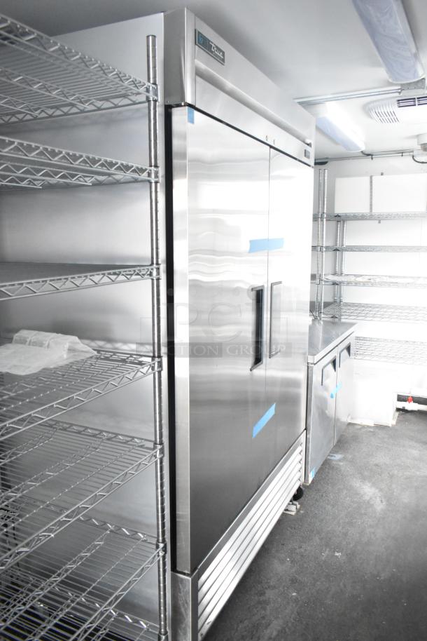 Cold food & beverage trailer interior with True cooler, Turbo Air appliances, and wire shelving. Commercial-grade setup.