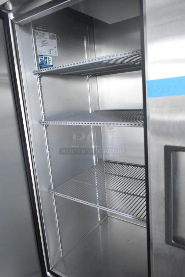 Interior of a commercial-grade True cooler with multiple wire shelves, ideal for cold food storage in a retail trailer setup.