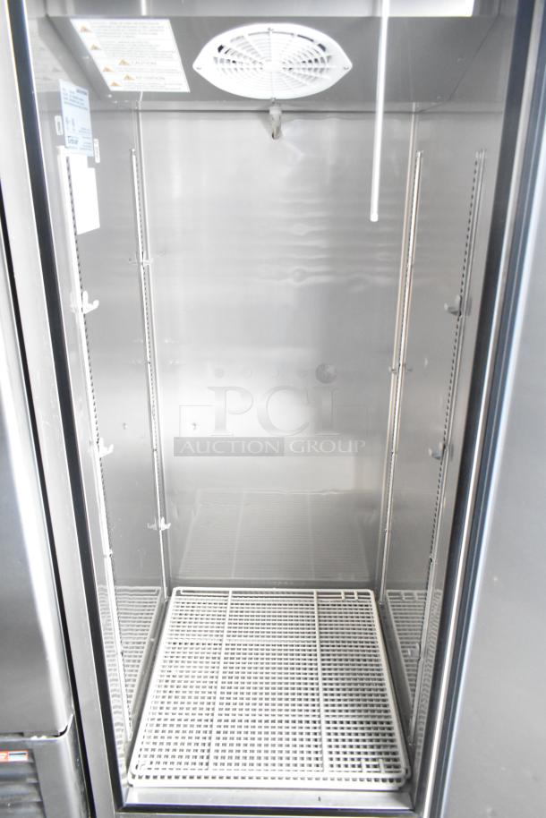 Interior view of a commercial-grade cooler from an unbranded food and beverage trailer, featuring wire shelving and cooling fan.